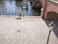 a paved walkway near the water with an umbrella on a pole above it's head