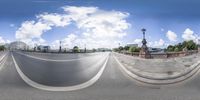 a panoramic view of a city intersection with white clouds above it and a person riding a skateboard