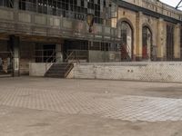 a boy riding a skate board in an industrial building yard near a brick wall with graffiti all over the walls