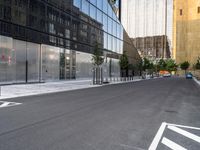 a street lined with parked cars next to large glass buildings near a city sidewalk or walkway