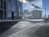 the empty street next to the buildings has several small squares in it and the building itself is reflecting in the windows