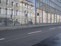 a large building is reflected in the side of the street that goes along this narrow road