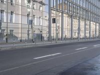 a large building is reflected in the side of the street that goes along this narrow road