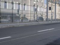 a large building is reflected in the side of the street that goes along this narrow road