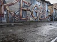 the wall of a building covered with graffiti in a city area that is dirty and has a man on a chair in it