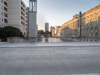 a skateboarder rides along the edge of a paved city street with tall buildings in the background