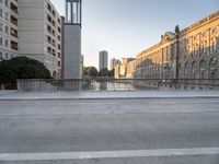 a skateboarder rides along the edge of a paved city street with tall buildings in the background