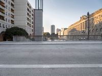 a skateboarder rides along the edge of a paved city street with tall buildings in the background