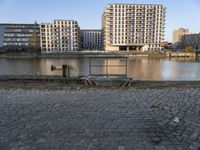 there is a bench near the water by it's bankside in the city