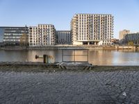 there is a bench near the water by it's bankside in the city