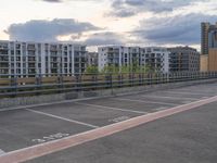 an empty parking lot on top of a concrete floor under cloudy skies over buildings and a highway