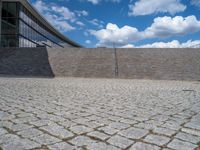 a person on a bike walking through a stone building entrance, in front of an enormous glass wall and stairs