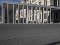 an empty city square with columns on the side and a person riding a bicycle down the street