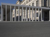 an empty city square with columns on the side and a person riding a bicycle down the street