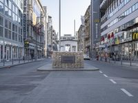 a city street scene with buildings in the background and a monument made of sandbags