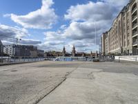 an empty parking lot surrounded by tall buildings and river front buildings with clock tower in the background