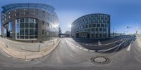 two buildings and street are reflected in a circular panoramic image on a blue sky day