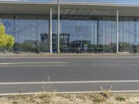 the front of the modern glassed building is reflected in the windows of its front