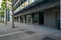 an empty street with tall buildings behind it and sidewalk area in front of the building