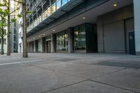 an empty street with tall buildings behind it and sidewalk area in front of the building