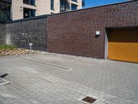 a brick wall with a small parking space near it and two garage doors opened to the street