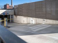 a large parking lot next to a tall metal building with a large window and door