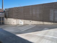 a large parking lot next to a tall metal building with a large window and door