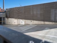 a large parking lot next to a tall metal building with a large window and door