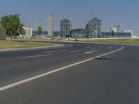 the street with two cars is empty in front of some city buildings by water in a sunny day