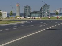 the street with two cars is empty in front of some city buildings by water in a sunny day