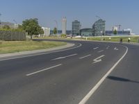 the street with two cars is empty in front of some city buildings by water in a sunny day