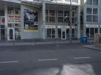 a street corner with an empty building in the background on a cloudy day and an open area to the left of the building is on display for sale signs and an advertisement