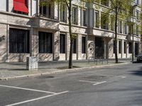 the buildings on the corner have large windows and doors and plants growing on them on the side of the street