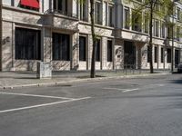 the buildings on the corner have large windows and doors and plants growing on them on the side of the street