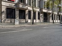 the buildings on the corner have large windows and doors and plants growing on them on the side of the street