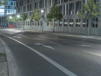 an empty street on a night time in front of some tall buildings and street lights