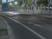 an empty street on a night time in front of some tall buildings and street lights