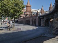 a man on his motorcycle sits next to the side walk of a street near an old building