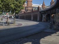 a man on his motorcycle sits next to the side walk of a street near an old building