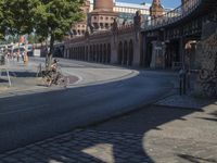 a man on his motorcycle sits next to the side walk of a street near an old building