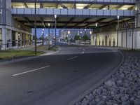 a bridge over the road in an empty city setting at dusk with blue lighting on its windows