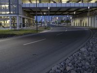 a bridge over the road in an empty city setting at dusk with blue lighting on its windows