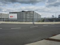 an empty street near a very large building under a blue sky with some fluffy clouds