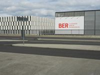 an empty street near a very large building under a blue sky with some fluffy clouds