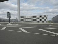 an empty street near a very large building under a blue sky with some fluffy clouds