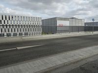 an empty street near a very large building under a blue sky with some fluffy clouds