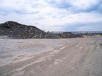 a construction area with many piles of rubble next to it and an overpass in the background