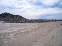 a construction area with many piles of rubble next to it and an overpass in the background