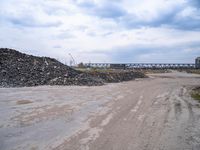 a construction area with many piles of rubble next to it and an overpass in the background