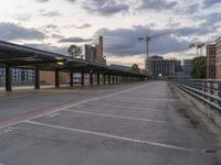 the empty parking lot of a city with construction crane in background and city lights above the building